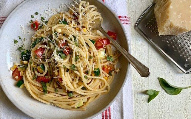 Spaghetti with tomatoes, corn, and zucchini on a plate