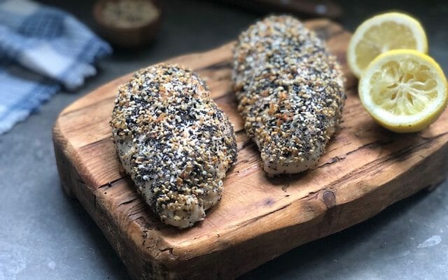 Everything seasoning chicken breasts on a cutting board