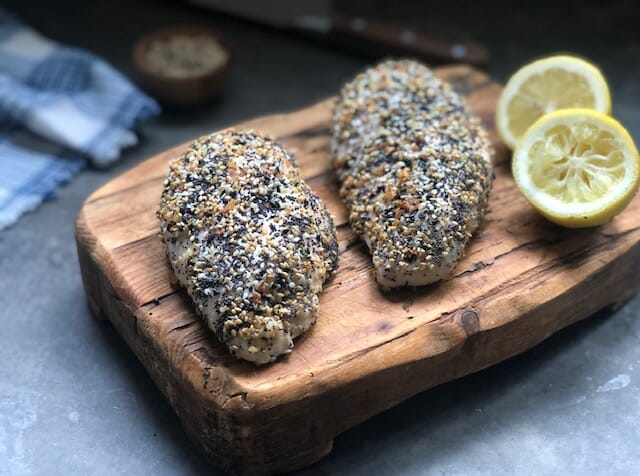 Everything seasoning chicken breasts on a cutting board