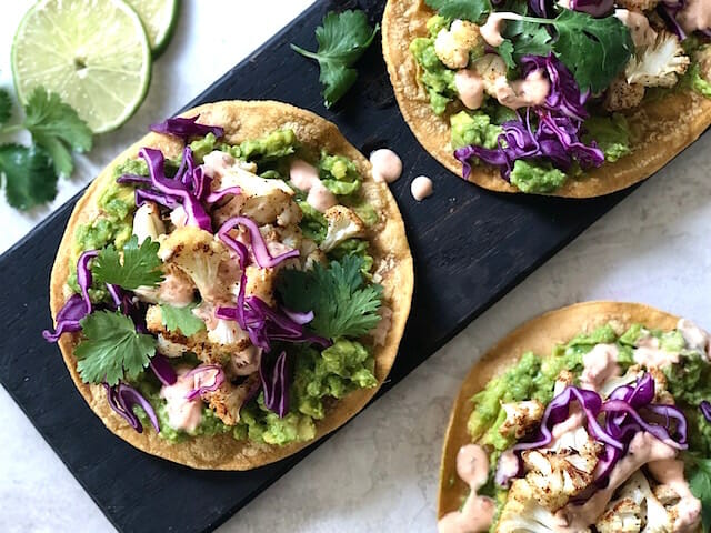 Cauliflower tostadas with avocado, cabbage and chipotle cream with lime slices