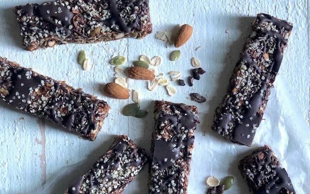 healthy chocolate hemp bars with dark chocolate drizzle and nuts and seeds on a white background