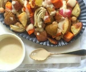 Platter of roasted vegetables with tahini dressing in a bowl with a spoon