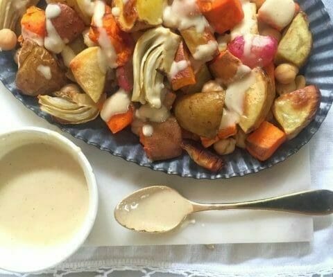 Platter of roasted vegetables with tahini dressing in a bowl with a spoon