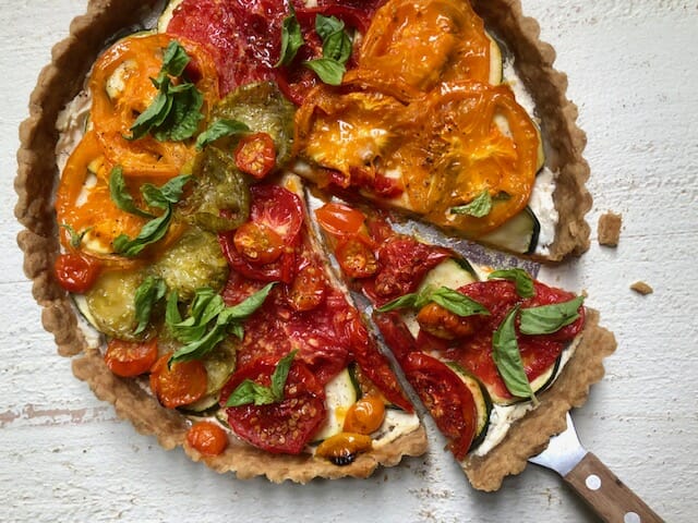 Tomato Zucchini Tart with a spatula and wedge of tart