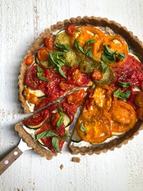 wedge of tomato zucchini tart in a whole tart