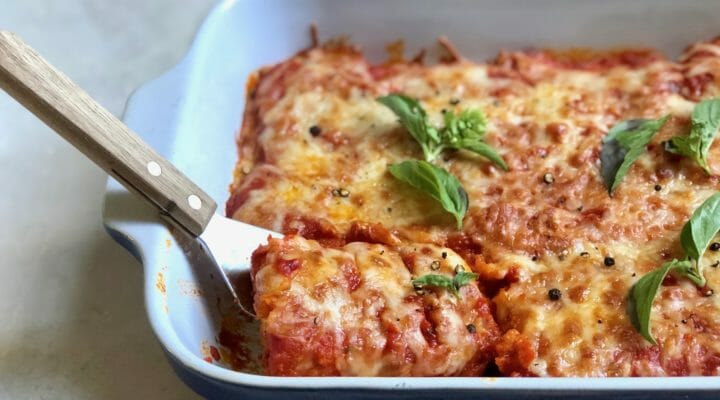 Oven Baked Tofu Parmesan with a spatula in a baking dish