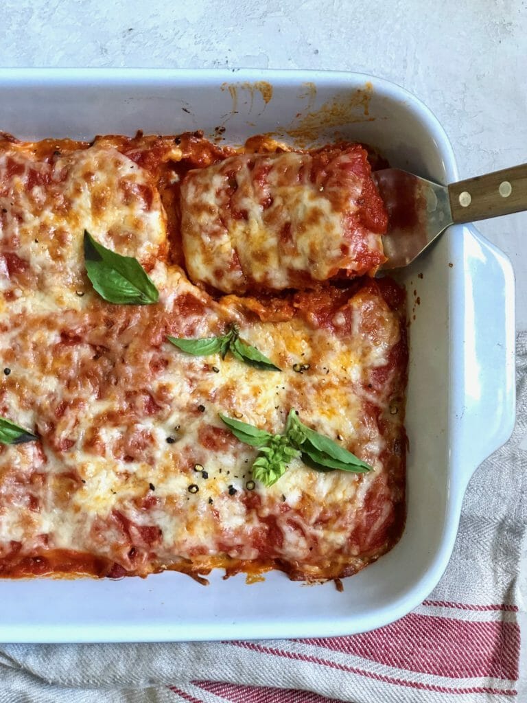 Tofu Parmigiana in baking dish with spatula and dish towel