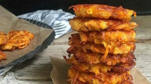 stack of 7 sweet potato and butternut squash latkes with more latkes on a plate