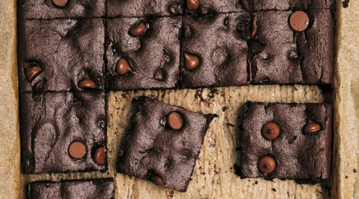 Chocolate and chocolate chip brownies made with sweet potato cut into squares on dark parchment paper