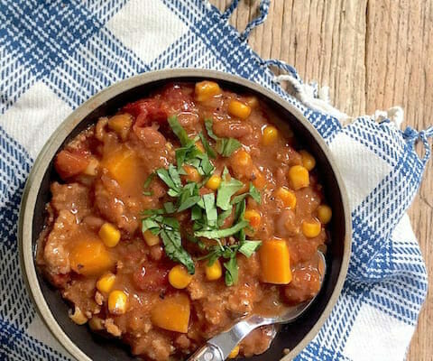 bowl of turkey chili with butternut squash on a blue and white kitchen towel