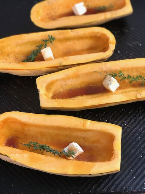 Delicata Squash on a baking sheet with butter and maple syrup