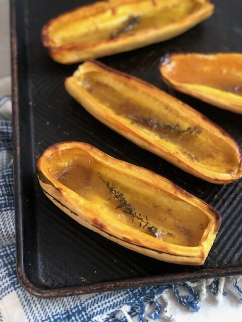 Roasted Delicata Squash with maple syrup on a baking sheet