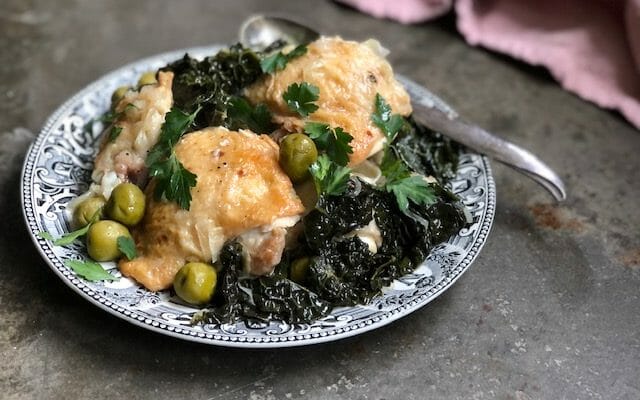 Instant pot chicken thighs olive and kale on a black and white plate and pink napkin