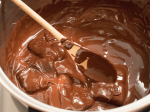 Big metal bowl of melted chocolate with a wooden spoon and 12 chocolate recipes