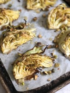 wedges of roasted cabbage on a sheet pan with pistachios