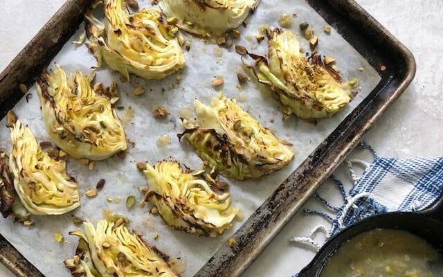 Wedges of roasted cabbages on a sheet pan with pan of miso butter