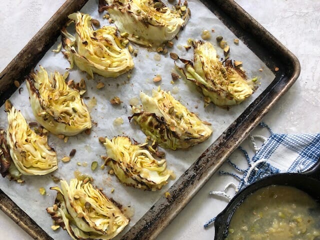 Wedges of roasted cabbages on a sheet pan with pan of miso butter