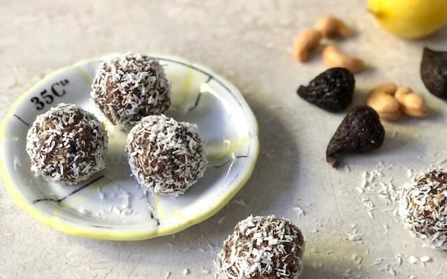 Coconut Fig Energy Balls on a small plate with cashew, lemon and whole figs