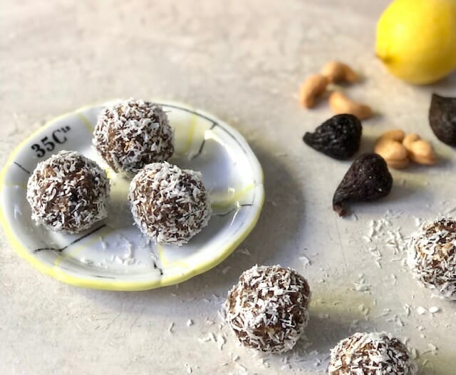 Coconut Fig Energy Balls on a small plate with cashew, lemon and whole figs