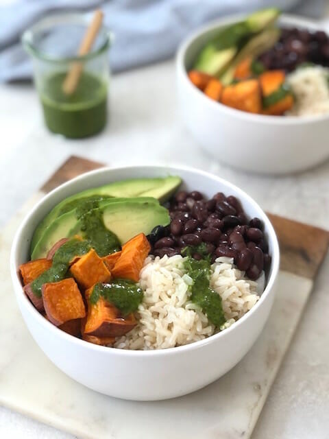 white bowls with sweet potato, black beans, and green sauce
