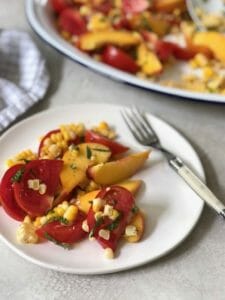 PEACH CORN TOMATO SALAD ON A WHITE PLATE WITH A FORK