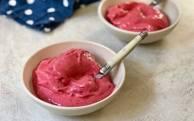 Two bowls of homemade raspberry sorbet with spoons and a navy polka dot napkin