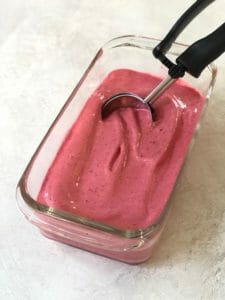 container of homemade raspberry sorbet with ice cream scoop