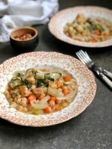 two bowls of chickpeas topped with croutons with forks and napkins