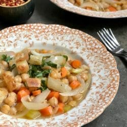 close up of brothy chickpeas with carrots and basil