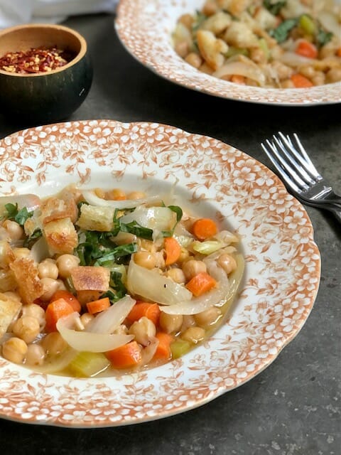 close up of brothy chickpeas with carrots and basil
