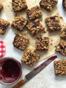 Jammy oatmeal crumble bars with an open jar of raspberry jam