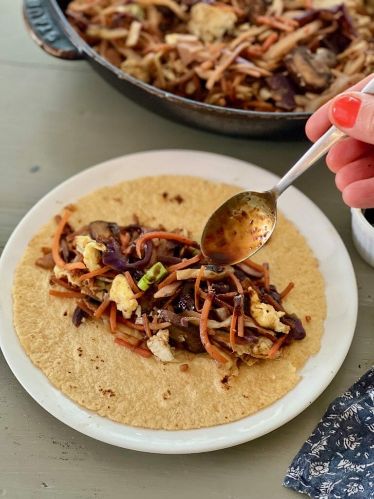 spooning sauce over moo shu vegetables