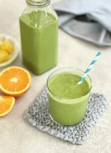 Pineapple Orange Green Smoothie in a glass with a striped straw