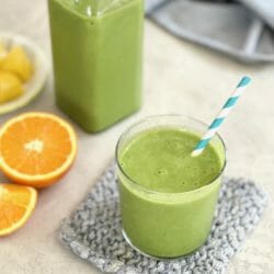 Pineapple Orange Green Smoothie in a glass with a striped straw