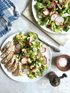 chopped salad with chicken on white plates with salt and pepper