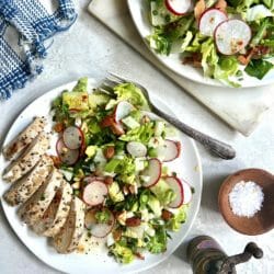 chopped salad with chicken on white plates with salt and pepper