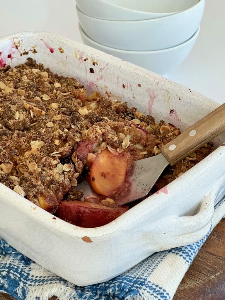 white pan with peach crisp and spatula