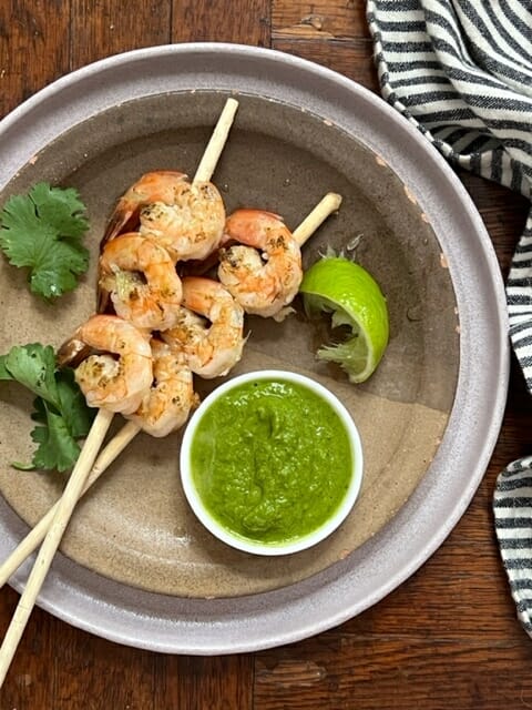 two shrimp skewers with green avocado sauce
