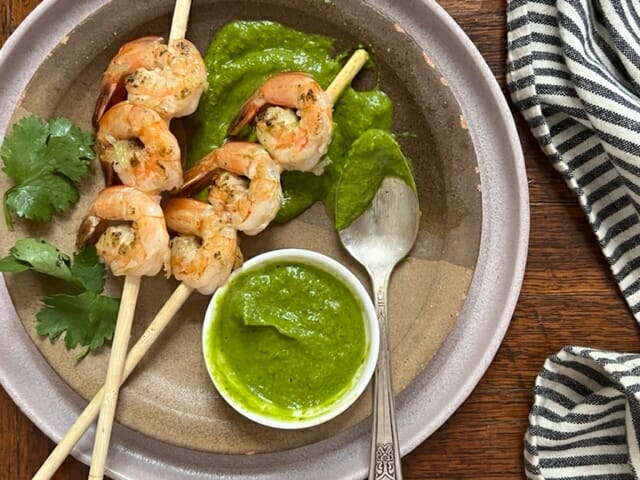 Plate of shrimp skewers with avocado herb sauce