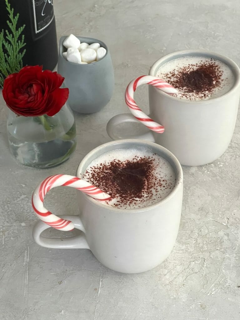 two mugs of mezcal hot chocolate with peppermint sticks