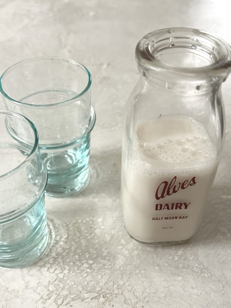 two glasses and a container of milk